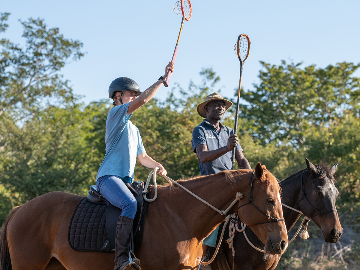 Image of a horse groom and volunteer skill fully practicing polo cross on horseback