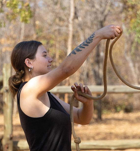 A young woman mastering natural horsemanship techniques amidst the African landscape.