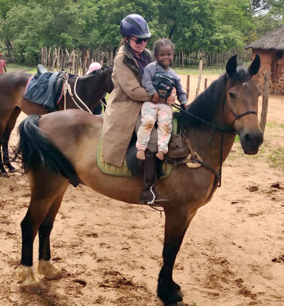 A woman and a child sharing a horseback ride through the captivating scenery of Africa.